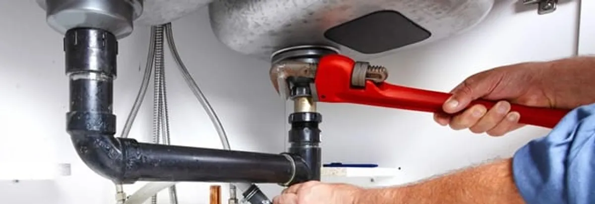 Garbage disposal repair technician tightening the sink drain and disposal connection in Mesa, AZ