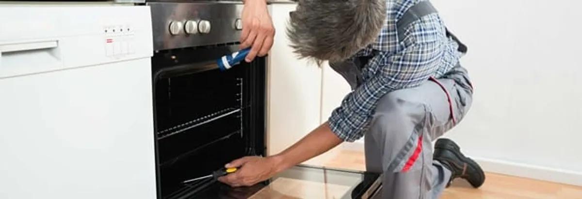 Oven repair technician inspecting and servicing an electric oven in Mesa, AZ