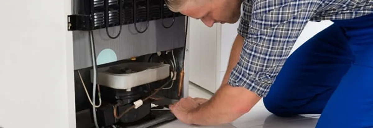 Refrigerator repair technician servicing the compressor and condenser area in Mesa, AZ