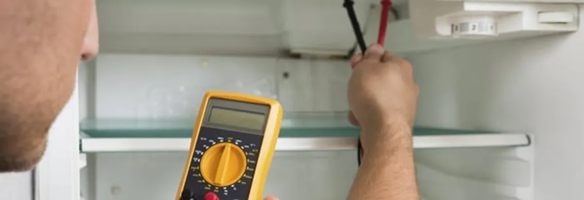 Refrigerator repair technician testing electrical components with a multimeter in Mesa, AZ
